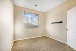 Carpeted spare room featuring visible vents and baseboards