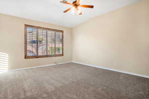 Spare room with lofted ceiling, carpet floors, ceiling fan, and baseboards