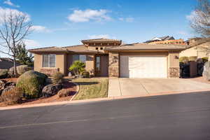 View of front facade featuring stucco siding, an attached garage, stone siding, driveway, and a tiled roof