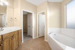 Bathroom with a bath, tile patterned flooring, vanity, and baseboards