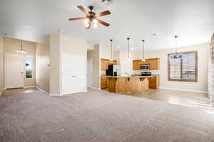 Kitchen featuring a breakfast bar area, light countertops, hanging light fixtures, appliances with stainless steel finishes, and light carpet