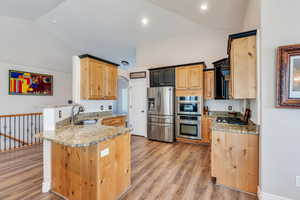 Kitchen featuring a peninsula, appliances with stainless steel finishes, light stone counters, and a sink