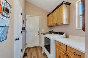 Laundry room featuring visible vents, washer and clothes dryer, light wood-type flooring, and cabinet space