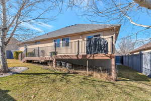 Rear view of house featuring a shingled roof, a lawn, fence private yard, a wooden deck, and stucco siding