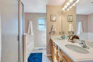 Full bath with a bath, double vanity, a sink, and tile patterned floors