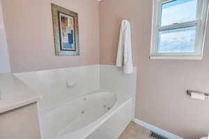 Full bath with tile patterned flooring, visible vents, a jetted tub, and baseboards