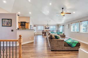 Living area with baseboards, a ceiling fan, vaulted ceiling, and wood finished floors