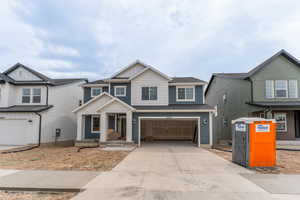 Craftsman-style house featuring board and batten siding, driveway, and an attached garage