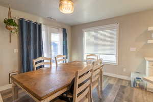 Dining space with visible vents, a textured ceiling, baseboards, and wood finished floors