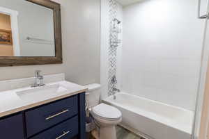 Bathroom with vanity, wood finished floors, shower / tub combination, and toilet