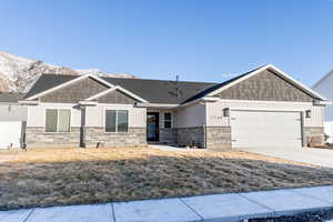 Craftsman house with a garage, concrete driveway, stone siding, a mountain view, and board and batten siding
