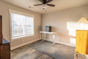 Unfurnished office with baseboards, visible vents, ceiling fan, and wood finished floors