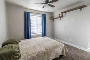 Carpeted bedroom with a ceiling fan, visible vents, and baseboards