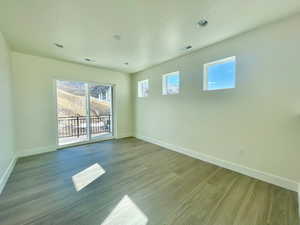 Spare room with wood finished floors, visible vents, and baseboards