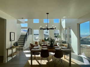 Dining area featuring wood finished floors, a healthy amount of sunlight, a notable chandelier, and stairs