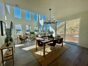 Dining space featuring a mountain view, wood finished floors, a towering ceiling, baseboards, and an inviting chandelier