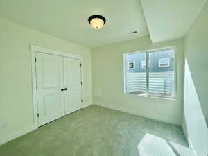 Unfurnished bedroom featuring baseboards, a closet, visible vents, and light colored carpet