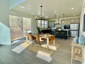 Dining space with recessed lighting, light wood-style flooring, a textured ceiling, a chandelier, and baseboards