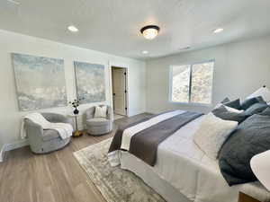 Bedroom featuring baseboards, visible vents, a textured ceiling, and light wood finished floors