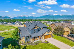 View of front facade with an attached garage, a mountain view, driveway, roof with shingles, and a residential view