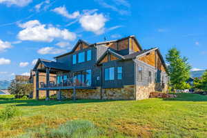 Back of house with stone siding and a lawn