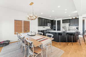 Dining area featuring a chandelier, light wood finished floors, baseboards, and recessed lighting