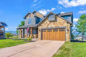 Craftsman-style home with covered porch, stone siding, and board and batten siding