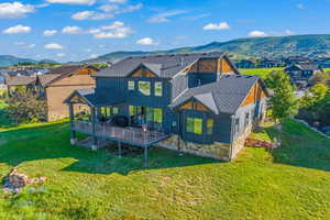 Back of property with a shingled roof, a residential view, and a yard