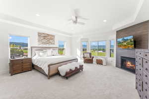 Bedroom featuring a large fireplace, multiple windows, a mountain view, and light colored carpet