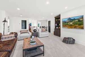 Living area featuring light carpet, baseboards, built in features, and recessed lighting