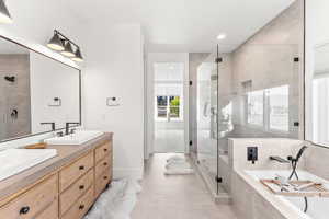 Bathroom with a garden tub, double vanity, a stall shower, a sink, and tile patterned floors