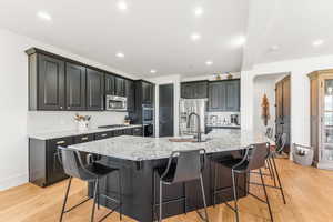 Kitchen with stainless steel appliances, a breakfast bar, a large island with sink, and tasteful backsplash