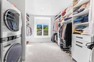 Walk in closet with light colored carpet and stacked washer / drying machine