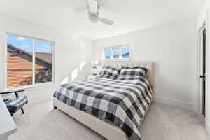 Bedroom with ceiling fan, multiple windows, baseboards, and light colored carpet