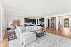 Living room with recessed lighting, visible vents, baseboards, light wood-style floors, and an inviting chandelier