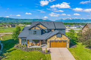 View of front of property with concrete driveway, roof with shingles, a residential view, and a mountain view