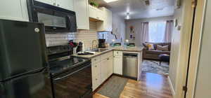 Kitchen featuring a peninsula, black appliances, light wood-style flooring, and white cabinetry