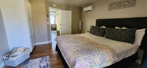 Bedroom featuring baseboards, dark wood-style flooring, and a wall mounted AC