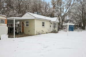 Snow covered house featuring central AC unit and a carport