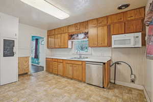 Kitchen with white microwave, a sink, visible vents, light countertops, and stainless steel dishwasher