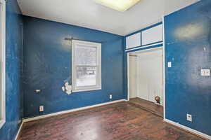 Empty room featuring a textured ceiling, baseboards, and wood finished floors