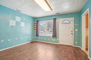 Entryway with visible vents, a textured ceiling, baseboards, and wood finished floors