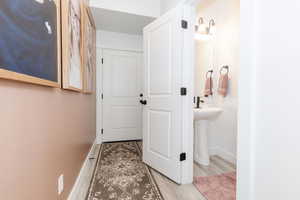 Hallway with a sink, baseboards, and wood finished floors