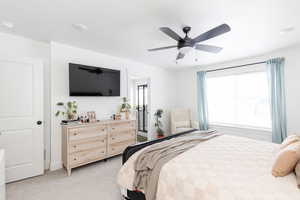 Bedroom with a ceiling fan and light colored carpet