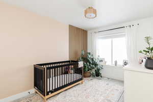 Bedroom with a nursery area, light colored carpet, visible vents, and baseboards