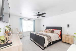 Bedroom with a ceiling fan and light colored carpet