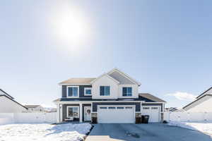 View of front of house featuring driveway, a garage, stone siding, fence, and board and batten siding