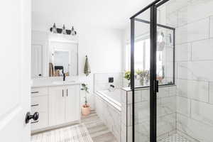 Full bathroom featuring a shower stall, a bath, and vanity