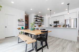 Dining room with light wood finished floors and recessed lighting