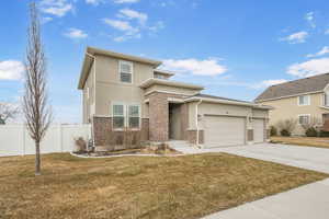 Prairie-style home featuring a garage, fence, concrete driveway, and brick siding